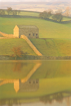 Barn and wall reflected in water at dusk, near Muker, Yorkshire Dales National Park, North Yorkshire, England, UK, Europe