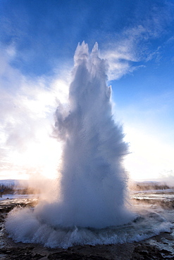 Strokkur Geysir erupting at sunrise on a freezing winter's morning against the colourful sky, Geysir, Haukardalur Valley, Iceland, Polar Regions