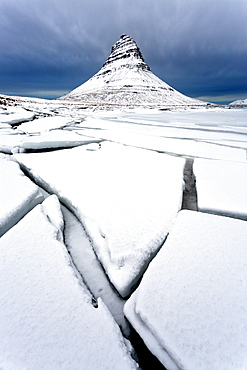 Winter view over slabs of broken lake ice covered in snow towards Kirkjufell (Church Mountain), near Grundarfjordur, Snaefellsnes Peninsula, Iceland, Polar Regions