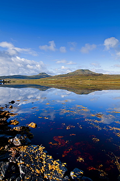 Craggy seascape of Loch Dunvegan on the Isle of Skye, with Macleod's Table in background., Isle of Skye, Inner Hebrides, Scotland, United Kingdom, Europe