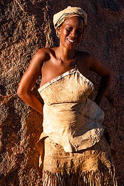 Portrait of woman resting against a rock in the sun at a Damara tribal village near Twyfelfontein, Namibia, Africa