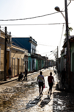 Typical backstreet with silhouetted young women walking down, Trinidad, Cuba