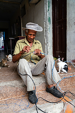 Electrician wiring himself in knots with his cats, Santa Clara, Cuba 2 (Model Release)