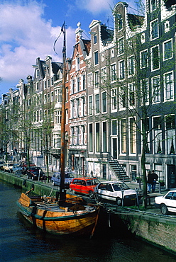 Netherlands, Amsterdam, Old Bricks Houses Along A Canal And Ancient Dutch Boat At Quay