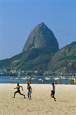 Brazil Rio De Janeiro.Children Playing Football On The Beach.Sugar Loaf Hill At Back