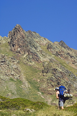 Hiker on climbing trail in hiking area of Pic de Coma Pedrosa, Andorra's highest mountain, Parish of La Massana, Andorra, Pyrenees, Europe