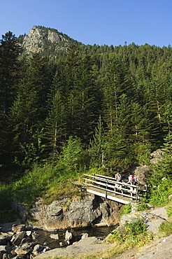 Hikers on bridge in hiking area of Pic de Coma Pedrosa, Parish of La Massana, Andorra, Pyrenees, Europe