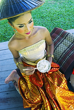 Girl in traditional Thai clothes eating rice, Phuket, Thailand, Southeast Asia, Asia