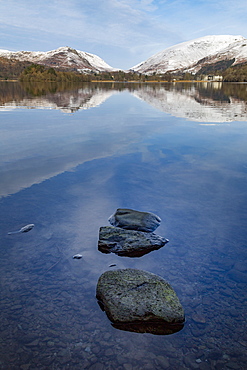 Stones in shallow water and perfect reflection of snow covered mountains and sky in the still waters of Grasmere, Lake District National Park, UNESCO World Heritage Site, Cumbria, England, United Kingdom, Europe