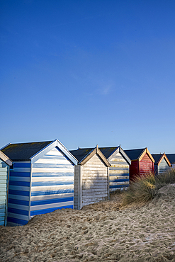 A row of colourful beach huts on the beach at Southwold in the county of Suffolk, East Anglia.