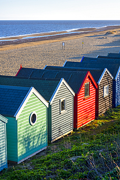 A row of colourful beach huts on the beach at Southwold in the county of Suffolk, East Anglia.