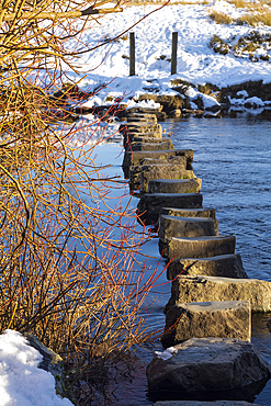 Stepping stones over the River Rothay in winter snow near Rydal Water in the Lake District National Park.