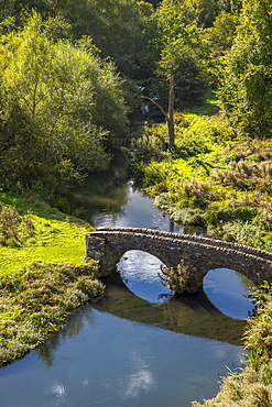 Ancient bridge over a river in the grounds of the historic Haddon Hall, dating back to Tudor times, in Derbyshire