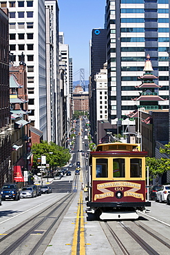 Cable car crossing California Street with Bay Bridge backdrop in San Francisco, California, United States of America, North America