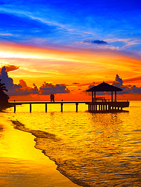 Couple on jetty looking at sunset, The Maldives, Indian Ocean, Asia