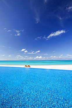 Deck chairs and infinity pool over amazing tropical lagoon, The Maldives, Indian Ocean, Asia