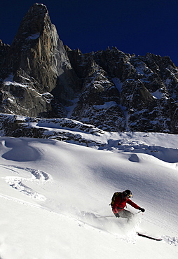 A skier enjoying perfect powder snow on the celebrated Pas de Chevre off-piste run, with the Dru in the background, Chamonix Valley, Chamonix, Haute Savoie, French Alps, France, Europe