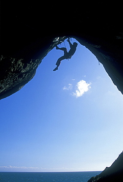 A climber ascending a cave archway at Foxhole, Gower Peninsula, Wales, United Kingdom, Europe