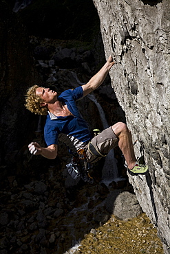 A rock climber tackles a very difficult route on the steep walls of Gordale Scar, a famous limestone ravine near Malham Cove, North Yorkshire, England, United Kingdom, Europe