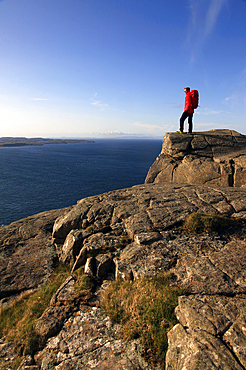 A hiker looks out to sea from cliffs at Fair Head, County Antrim, Ulster, Northern Ireland, United Kingdom, Europe