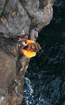 A climber deep water soloing above the sea on the limestone cliffs near St. Govan's Head, South Pembrokeshire, Pembrokeshire Coast National Park, Wales, United Kingdom, Europe