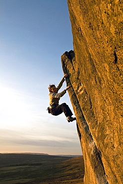 A climber on a popular gritstone bouldering route on the Plantation Boulders at Stanage Edge, Peak District National Park, near Hathersage, Derbyshire, England, United Kingdom, Europe