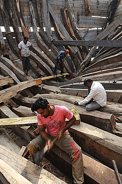 Carpenters working to build an ocean going wooden dhow entirely by hand, Mandvi shipyard, Gujarat, India, Asia