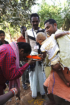 Mali tribesman offering puja gift to temple pundit after shaving his child's head at the festival of Shivraatri, Koraput, Odisha, India, Asia