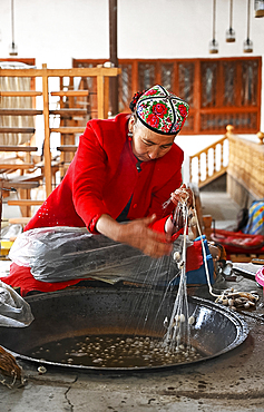 Uyghur woman spinning silk thread from cocoons in traditional silk workshop, Jiya, Xinjiang, China, Asia