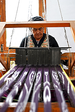 Uyghur woman at loom weaving tie dyed silk thread into traditional cloth, Jiya, Xinjiang, China, Asia