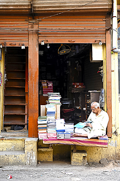 Bookseller sitting outside his bookshop in old Ahmedabad, Gujarat, India, Asia