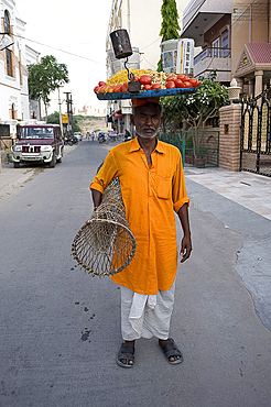 Man in yellow kurta with tray of snacks on his head and table under his arm, to sell in the market, Jodhpur, Rajasthan, India, Asia