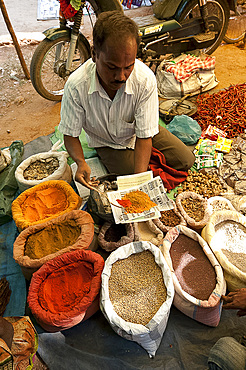 Spice stall at Desia Kondh tribal market, man spooning turmeric, cumin and chilli powder for customer, near Rayagada, Orissa, India, Asia