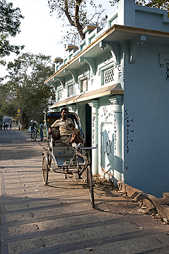 Cycle rickshaw wallah waiting for fare next to a riverside shrine on the banks of the Hooghly River, Serampore, West Bengal, India, Asia