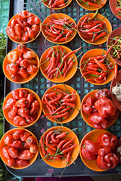 Colourful red chillies and capsicums on orange plates on a market stall in Kuching, Sarawak, Malaysian Borneo, Malaysia, Southeast Asia, Asia