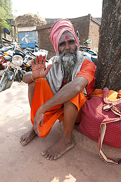 Travelling saddhu dressed in holy colour orange, resting beneath a village tree, Bhubaneshwar, Orissa, India, Asia