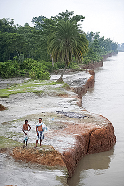 Two village men on the distinctive red sandstone banks of the Brahmaputra River at Bijaynagar, Assam, India, Asia