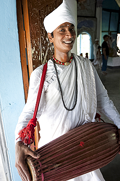 Gayan (musician) dressed in white cotton, with horizontal khol drum at the Uttar Kamalabari Hindu monastery, Majuli Island, Assam, India, Asia