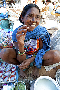 Smiling Mali tribeswoman with gold noserings selling yoghourt in Mali weekly tribal market, Guneipada, Orissa (Odisha), India, Asia