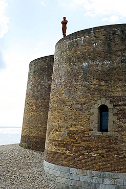 Antony Gormley's sculpture of a man looking out to sea, standing on the Napoleonic Martello tower in Aldeburgh, Suffolk, England, United Kingdom, Europe