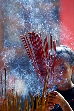 Woman praying with burning incense sticks, Ong Bon Pagoda, Taoist Temple, Ho Chi Minh City, Vietnam, Indochina, Southeast Asia, Asia