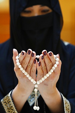 Close up of a Muslim woman's hands in abaya while holding rosary and praying, United Arab Emirates, Middle East