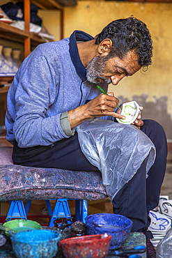 Worker painting dishes in a pottery workshop, Safi, Morocco