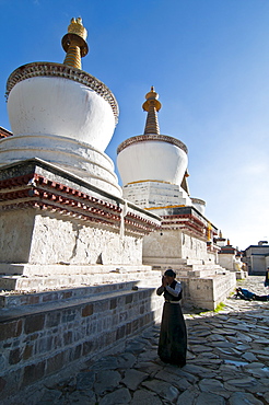 Pilgrim in front of the white stupas at the Tashilumpo monastery, Shigatse, Tibet Autonomous Region, China, Asia