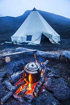 Boiling water pot over an open fire on a campsite and tipi on Tolbachik volcano, Kamchatka, Russia, Eurasia