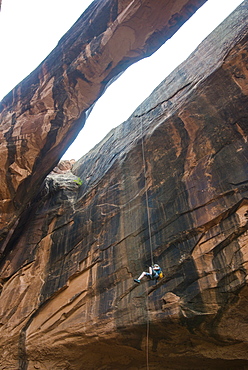 Woman rapelling down a giant arch, canyoneering, Moab, Utah, United States of America, North America