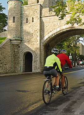 Cyclists riding past the Porte Saint Louis, Quebec City, Quebec, Canada, North America