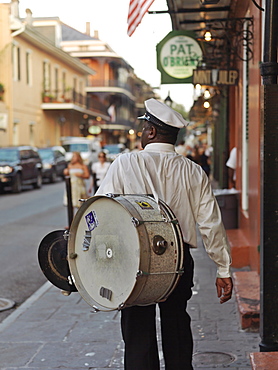 Second line parade musician walking along street with drum, French Quarter, New Orleans, Louisiana, United States of America, North America