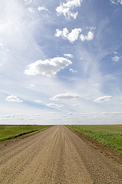 Clouds and blue sky over a dirt track in the Badlands of Alberta, near Drumheller, Alberta, Canada, North America