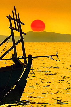 Big red setting sun beyond fishing boat moored off beach south of the city, Otres Beach, Sihanoukville, Cambodia, Indochina, Southeast Asia, Asia